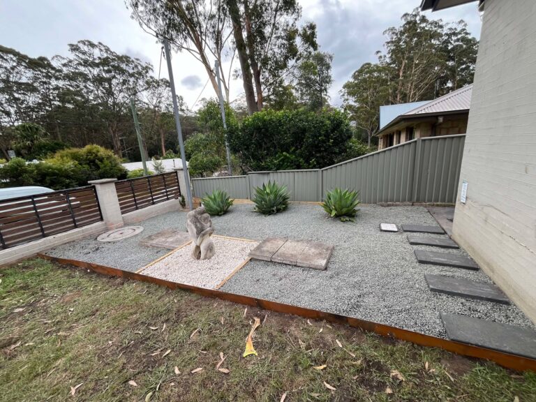 A finished landscaped area with gravel, stepping stones and new garden beds beside a house